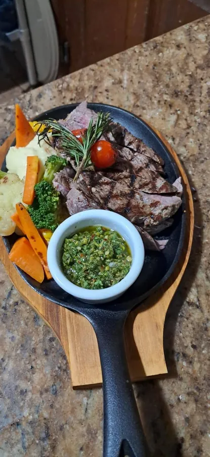 Steak on a cast iron skillet with chimichurri