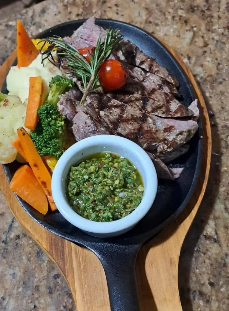 Steak on a cast iron skillet with chimichurri